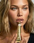 Woman holding a gold lip balm with 'Lip FILA' branding.