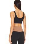 Nubyen Alicante V-Neck Wrap Sports Bra in Biscotti. The bra features a flattering wrap design, deep V-neckline, and smooth fabric for a stylish yet supportive fit. Styled with matching activewear, the look is showcased in a clean, modern setting with soft lighting to emphasize its neutral tone.