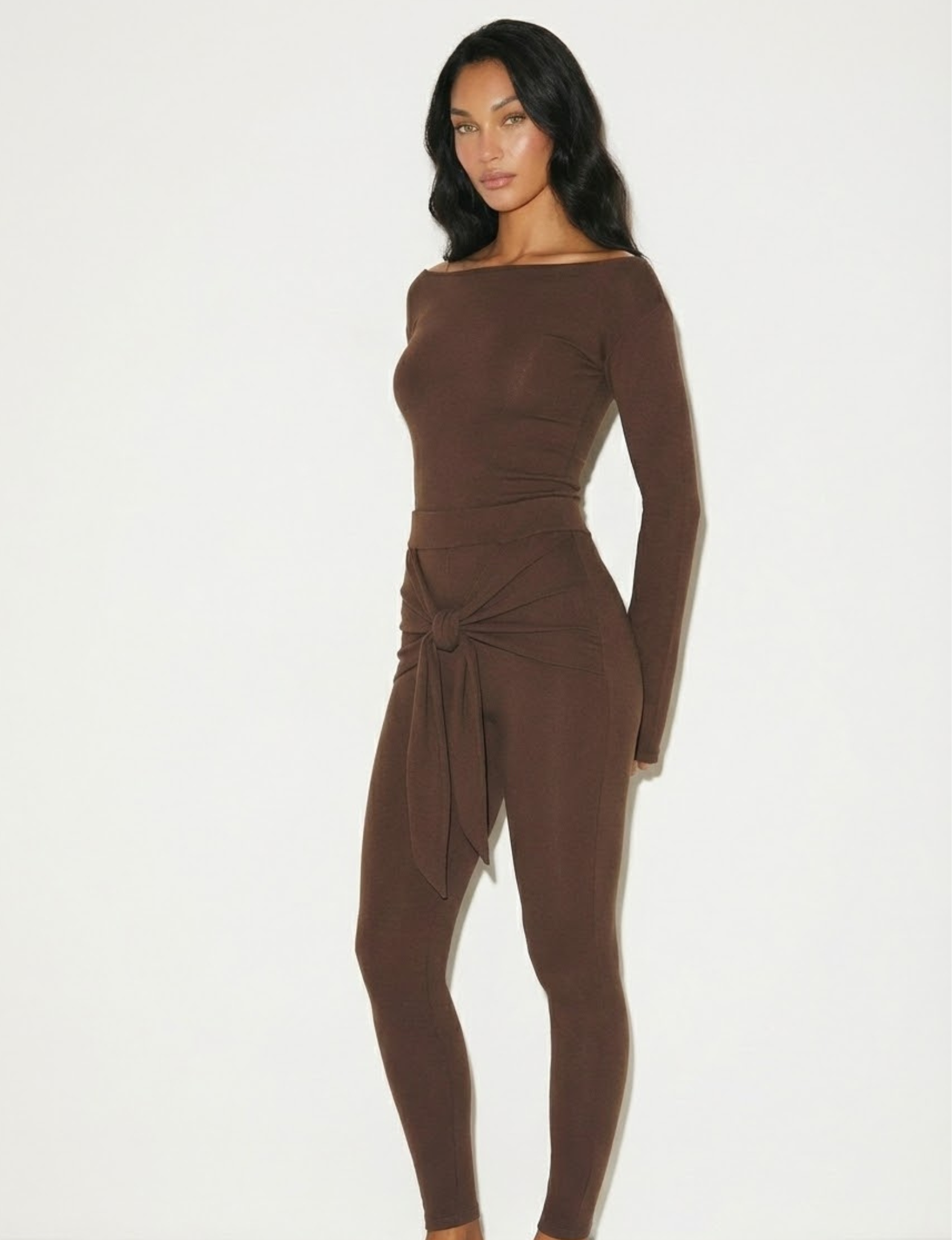 Romy Knit Pants in chocolate brown, featuring a high-waisted fit, soft knit fabric, and a front-tie detail for a stylish and comfortable look. Perfect for casual or elevated cozy outfits

Romy Knit Top styled in a minimalist setting. Featuring a sleek, fitted design with a boat neckline and ribbed texture, it exudes contemporary elegance. Soft lighting and neutral tones enhance its sophisticated appeal."