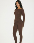 Romy Knit Pants in chocolate brown, featuring a high-waisted fit, soft knit fabric, and a front-tie detail for a stylish and comfortable look. Perfect for casual or elevated cozy outfits

Romy Knit Top styled in a minimalist setting. Featuring a sleek, fitted design with a boat neckline and ribbed texture, it exudes contemporary elegance. Soft lighting and neutral tones enhance its sophisticated appeal."