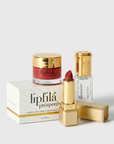 A luxury skincare and lip care set featuring a red lipstick, a gold-lidded jar of lipfilá prosperity cream, a clear bottle of the Minimalist Sunscreen, and their white and gold packaging boxes, arranged on a clean white background.