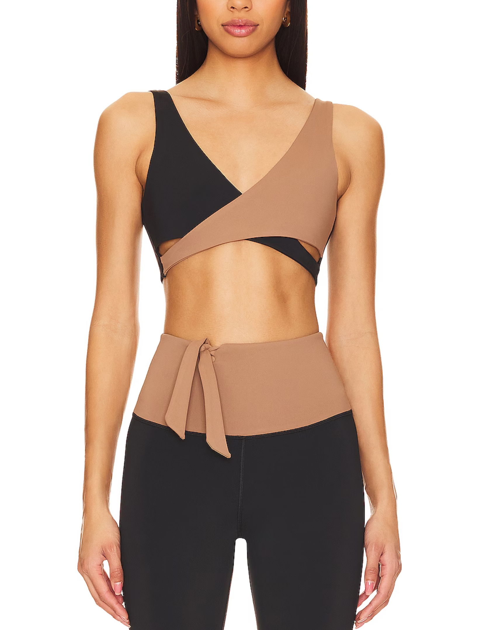 Nubyen  Abundance V-Neck Wrap Sports Bra in Biscotti. The bra features a flattering wrap design, deep V-neckline, and smooth fabric for a stylish yet supportive fit. Styled with matching activewear, the look is showcased in a clean, modern setting with soft lighting to emphasize its neutral tone.