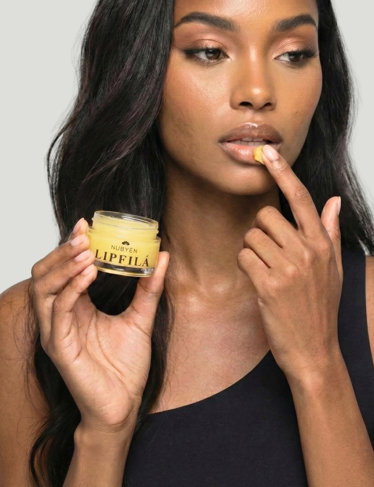 Nubyén Lipfilá lip plumping elixir shown with its white outer box, a gold inner tray, and the open jar placed on top. BEST SELLER