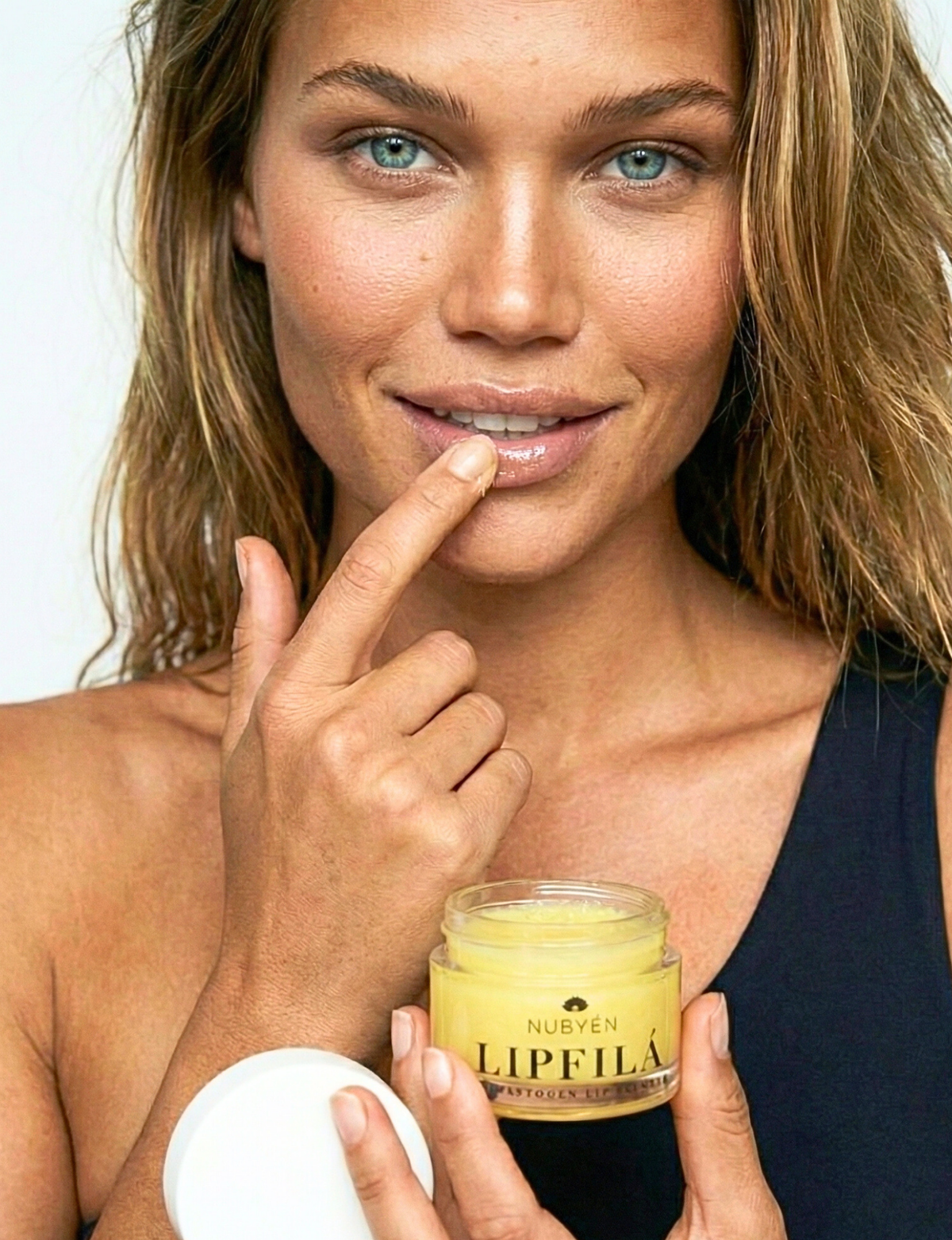 Nubyén Lipfilá lip plumping elixir shown with its white outer box, a gold inner tray, and the open jar placed on top. BEST SELLER