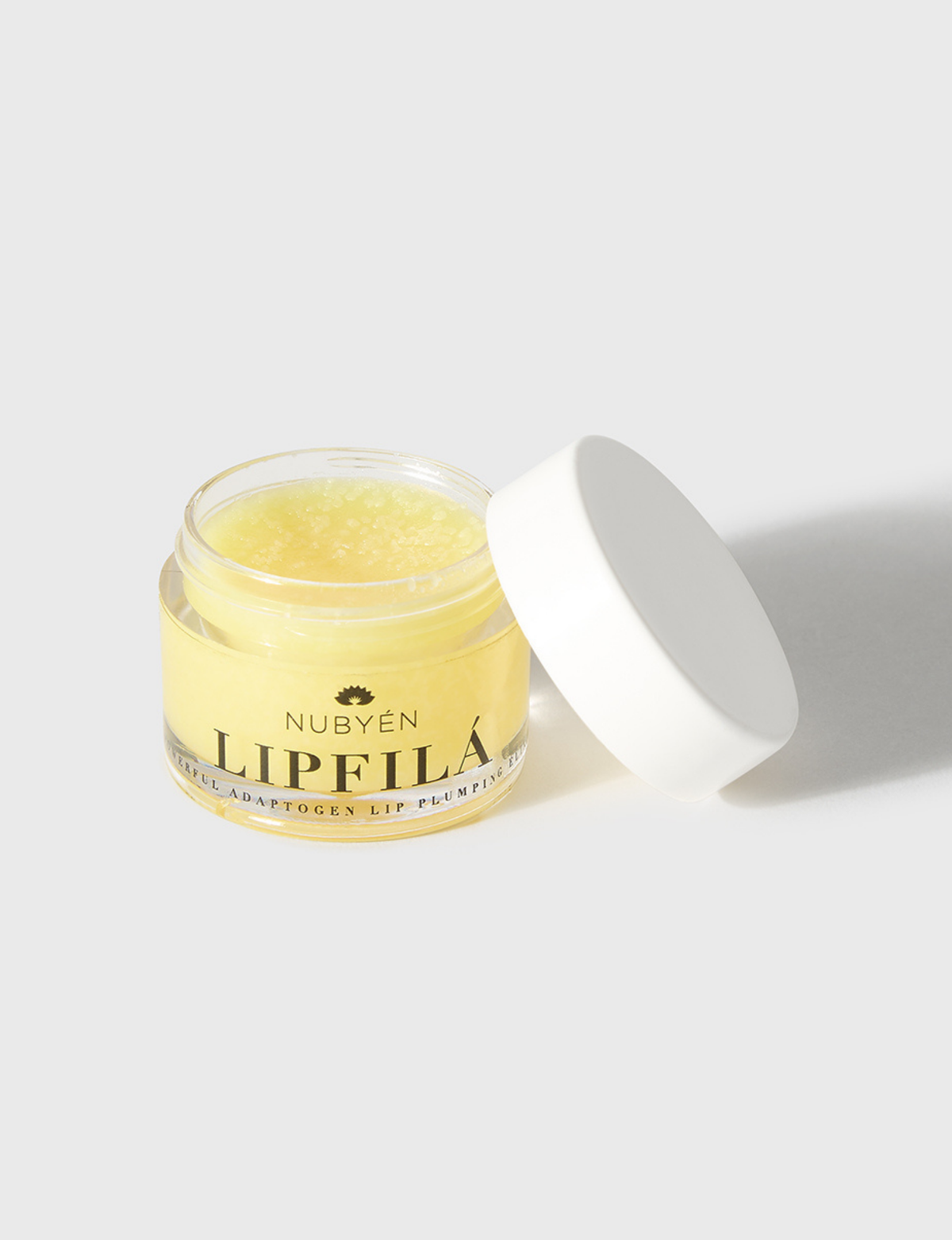 Nubyén Lipfilá lip plumping elixir shown with its white outer box, a gold inner tray, and the open jar placed on top. BEST SELLER
