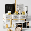 A luxury makeup and skincare set featuring Nubyen Lipfila products, including lip scrub, lip gloss, lipsticks, a bronzer, and brushes, arranged on a light gray background.