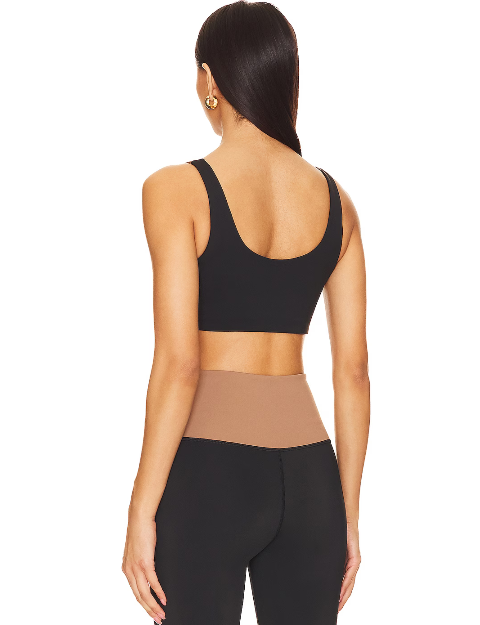 Nubyen Alicante V-Neck Wrap Sports Bra in Biscotti. The bra features a flattering wrap design, deep V-neckline, and smooth fabric for a stylish yet supportive fit. Styled with matching activewear, the look is showcased in a clean, modern setting with soft lighting to emphasize its neutral tone.