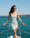 Sage green fitted athletic mini dress with soft cream contrast trim, body-contouring stretch fabric and minimalist sleeveless silhouette designed for elevated activewear, tennis-inspired styling and luxury everyday wear.